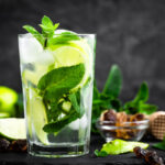 Refreshing mint cocktail mojito with rum and lime, cold drink or beverage with ice on black background